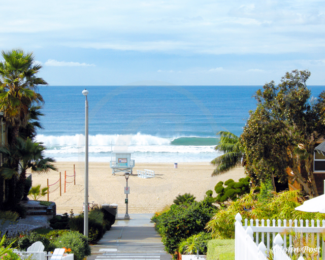 View down walk street to ocean, wave, beach and lifeguard tower.